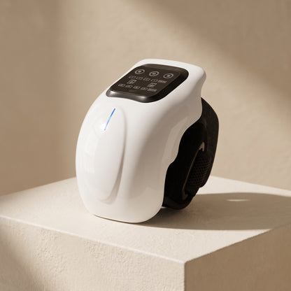 The knee massager seen from three-quarters on a warm ivory pedestal, its control panel and blue indicator light showing
