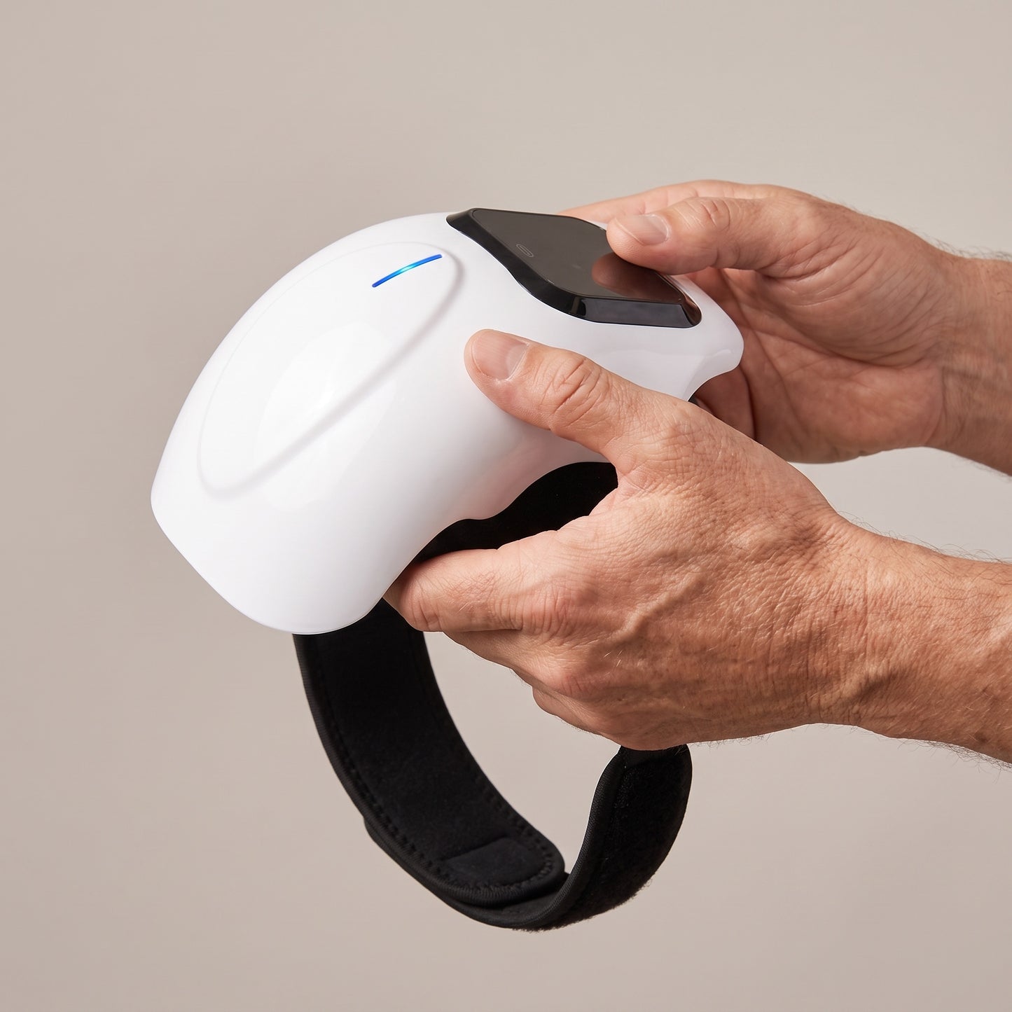 The knee massager held in two hands to show how large it is