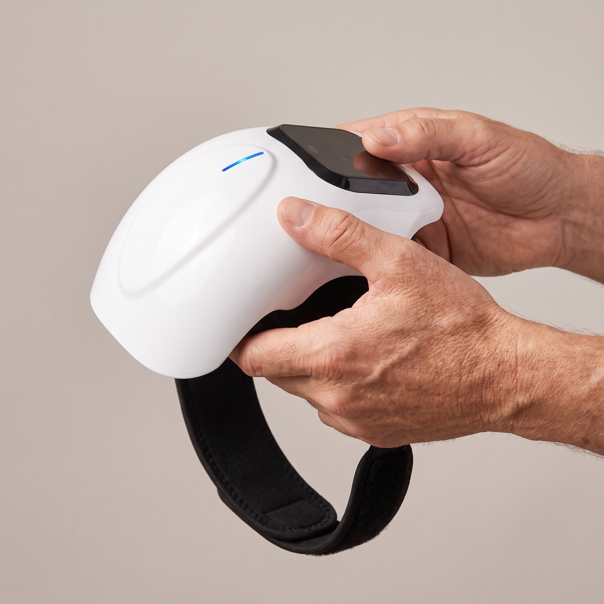 The knee massager held in two hands to show how large it is